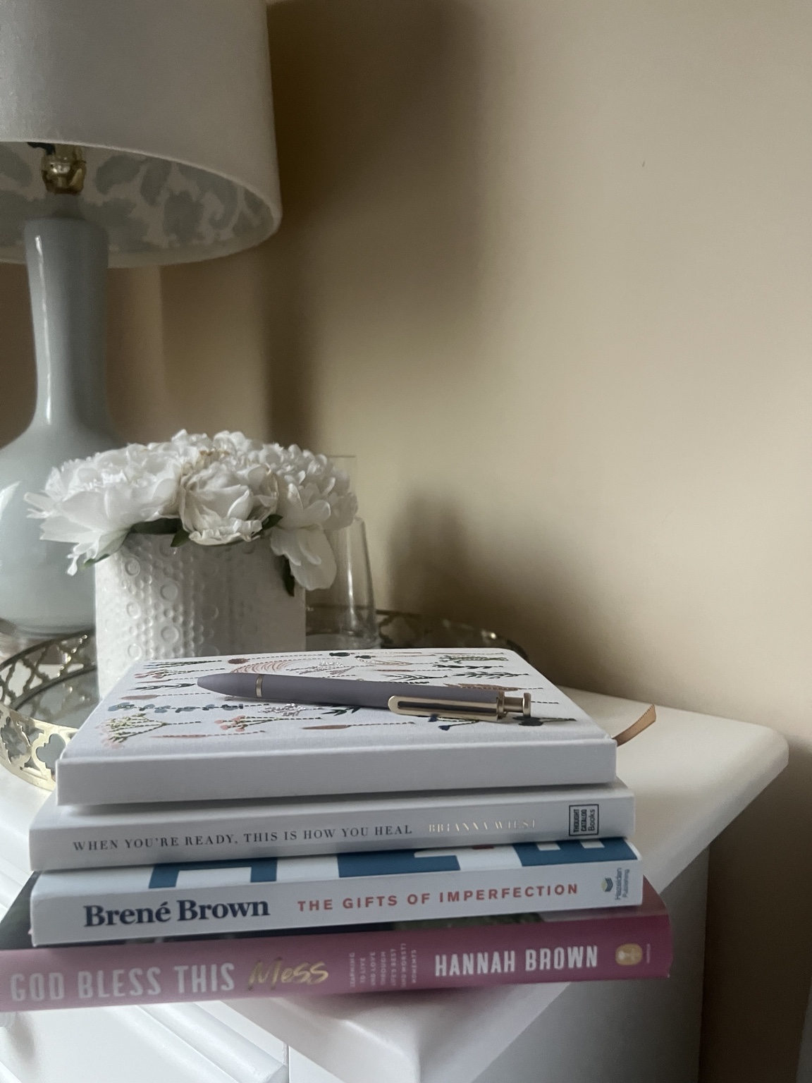 A journal and thoughtful books on a bedside table