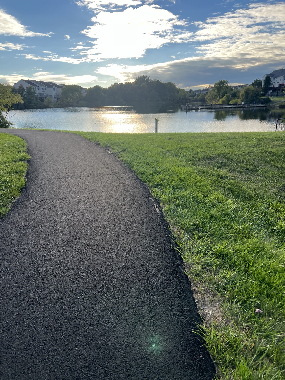 A quiet walking path beside a lake beneath a blue sky